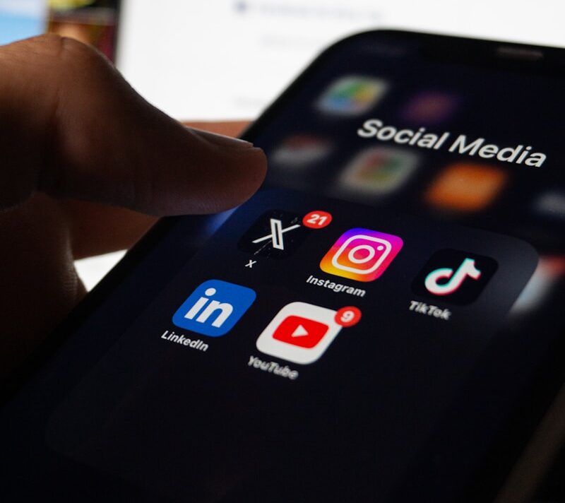 A person holding a smart phone with social media on the screen